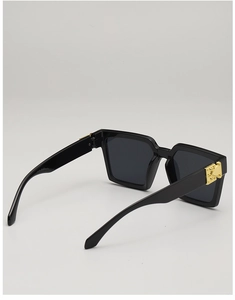Detail of square black sunglasses with gold metal rivets and deep grey lenses