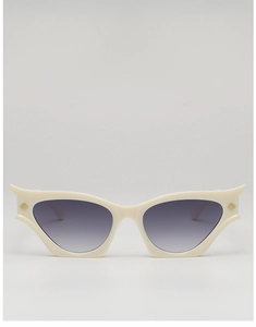 Detail view of cat eye sunglasses with cream frame and gold wing logo decoration