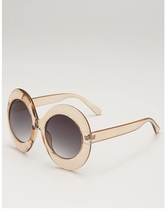 Detail view of champagne oval sunglasses with thick frames and gradient grey lenses