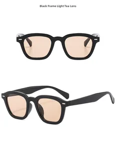 Detail of square black sunglasses with light brown lenses and silver rivets on the frame