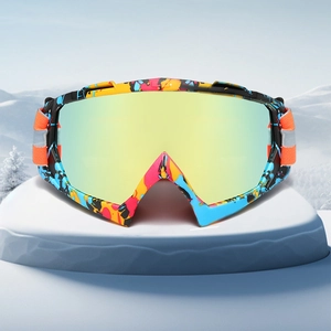 Graffiti style ski goggles with gold mirror lens and orange strap on a snowy background