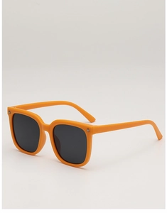 Macro shot of orange rectangular kids sunglasses with silver star studs on a white background