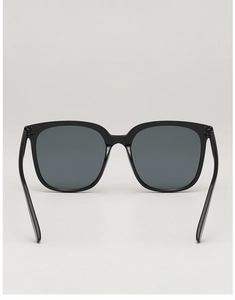Detail shot of oversized black square sunglasses with polished frames and dark gray lenses