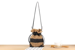 Detail of handwoven straw bucket bag with black stripes and a leather drawstring