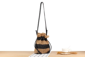 Detail of handwoven straw bucket bag with black stripes and drawstring closure