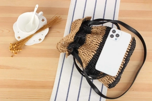 Top-down view of woven striped bucket bag with drawstring and thin black shoulder strap