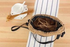 Detailed top view of a woven bucket bag with drawstring liner and leather shoulder strap