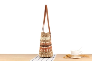 Détail d'un sac à bandoulière tressé à rayures colorées et sangle en cuir sur une table