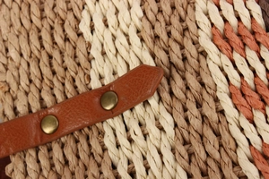 Détail macro du sac tissé multicolore avec sangle en cuir brun et rivet métallique