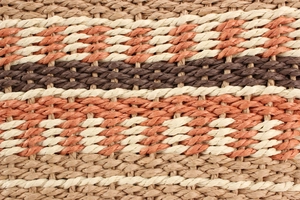 Détail macro de la texture en paille tressée multicolore aux tons naturels et orange