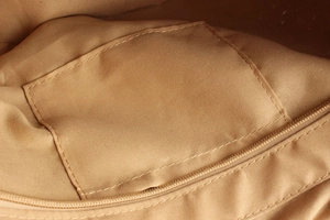 Détail intérieur du sac à bandoulière montrant la doublure lisse et la poche zippée