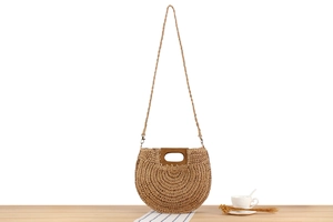 Detailed macro view of the woven natural straw texture and smooth wooden handle of the handbag