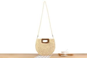 Detailed close-up of a semi-circular straw bag with brown wooden handle and woven texture