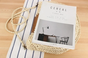 Detail of hand-woven beige straw bag with wooden frame handle and long braided shoulder strap