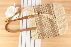 Détail d'un sac de plage tressé avec pompon à franges et poignées en cuir marron