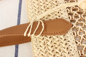 Détail de la texture en paille tressée et de la poignée en cuir marron du sac à main