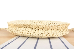Detailed side and bottom view showing tight weave texture of round straw bag
