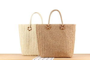 Détail de sacs fourre-tout tissés en beige et marron naturel avec anneaux de poignée