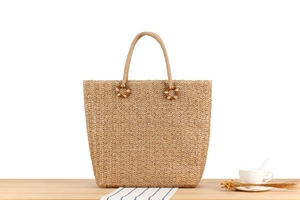 Gros plan détaillé d'un sac cabas en paille tissé à la main avec poignées en bois sur table
