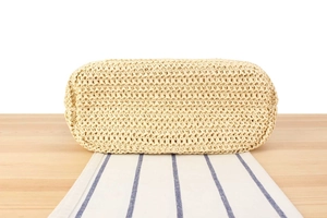 Gros plan de la base ovale tressée du sac en paille beige avec détails de texture
