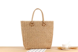 Détail du tissage en V d'un sac cabas en paille naturelle sur une table en bois pour l'été