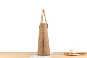 Gros plan du sac cabas en paille tissée avec anneau en bois foncé et texture naturelle