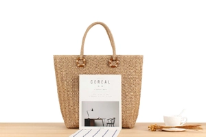 Détail du tissage et de la poignée en anneau de bois brun foncé sur ce sac cabas en paille