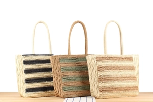 Detail of three handmade woven beach tote bags with round handles on a wooden table