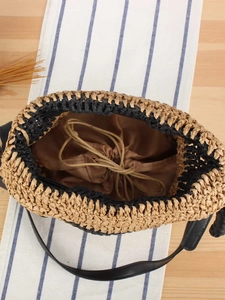 Handcrafted woven straw bucket bag with drawstring liner and black leather shoulder strap