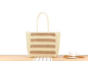 Detail of hand-woven straw tote bag with striped pattern on wooden background