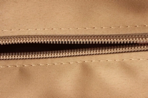 Gros plan sur les dents de fermeture éclair kaki et les coutures renforcées du sac fourre-tout
