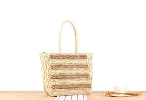 Close-up of natural straw woven tote bag with brown stripes and sturdy braided handles