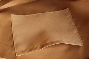 Gros plan détaillé de la poche intérieure et des coutures renforcées d'un sac cabas marron