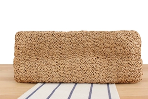 Détail d'un sac cabas tissé avec texture en V sur surface en bois et tissu rayé
