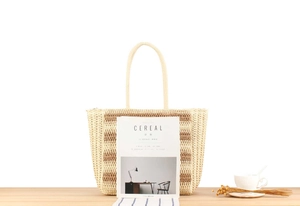 Detail of large woven beach tote with beige and brown stripes on wooden surface