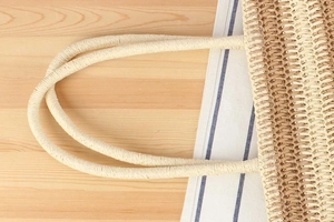 Close-up of thick woven handles and straw texture on a large beach tote bag