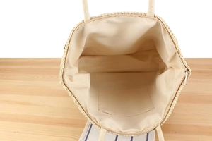 Detail of hand-woven straw tote bag with zipper closure and beige fabric interior lining