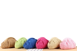 Detail of colorful woven straw clutch bags with gold metal chain straps and textured finish