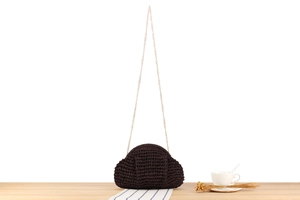 Detailed texture of dark brown hand-woven crochet bag with delicate gold chain strap