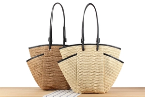 Detail of hand-woven straw tote bags with black leather trim and side pockets in two colors