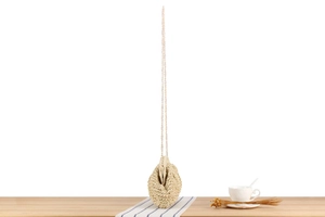 Detail of woven straw bag with gold chain strap and interior lining on a wooden table