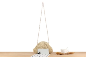 Detail of hand-woven cream crossbody bag with gold chain strap and smartphone for size scale