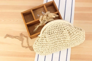 Flat lay of a beige woven cloud bag with gold chain strap on natural wooden background