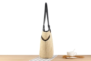 Close-up of beige straw woven tote bag texture with black trim on a cafe table