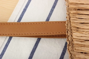 Close-up of fringe woven texture and brown leather strap with reinforced stitching
