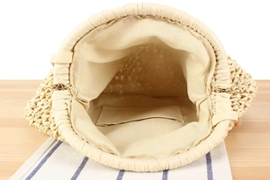 Internal view of cream woven bag showing beige fabric lining and gold metal hinges