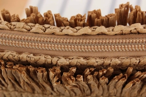 Detailed close-up of woven straw bag showing fringe edges and smooth nylon zipper