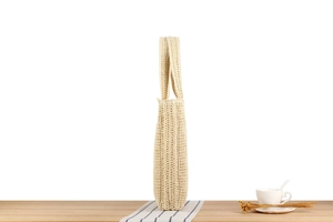 Detail of cream woven tote bag with hollow mesh pattern on a minimalist wooden surface