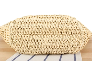 Detailed macro view of the oval base on a handmade woven straw bag with cross-stitch pattern