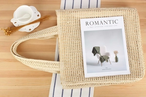 Detail of woven straw tote bag featuring a large mesh pattern for a beach vacation look